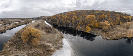 River curve panorama autumn aerial, yellow leaves on trees growing on riverside with cloudy sky in Ukraine