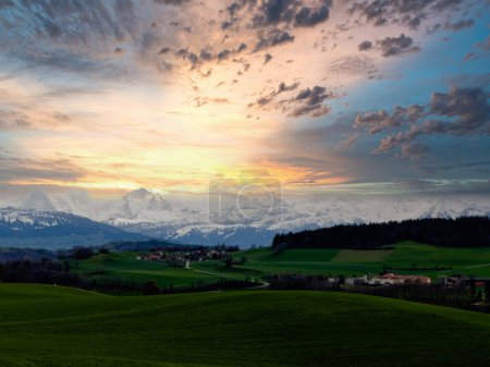 Stunning sunset over a lush Swiss landscape, featuring a winding