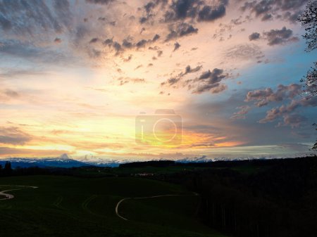 Impresionante puesta de sol sobre un exuberante paisaje suizo, con un sinuoso