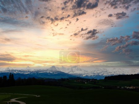 Stunning sunset over a lush Swiss landscape, featuring a winding