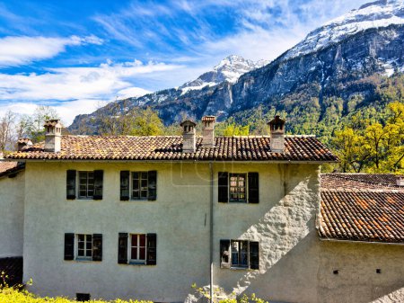 Traditionelles europäisches Bauernhaus mit offenem Hof, mit mehreren Ebenen von Balkonen, Sichtbalken und alten hölzernen Bauernkarren, die vor einem strahlend blauen Himmel stehen