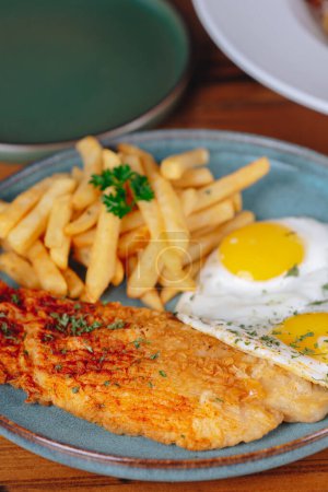Foto de Un plato de comida con un huevo frito, un trozo de pescado y unas papas fritas - Imagen libre de derechos