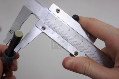 Foto de Measuring a metal shaft with two-handed calipers - Imagen libre de derechos