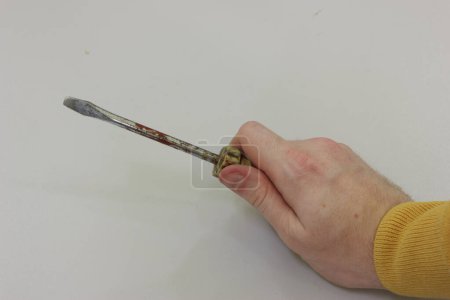 Foto de Minus screwdriver in a man's hand on a gray background - Imagen libre de derechos