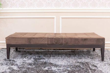 Foto de Un banco marrón largo, y una alfombra mullida gris - Imagen libre de derechos