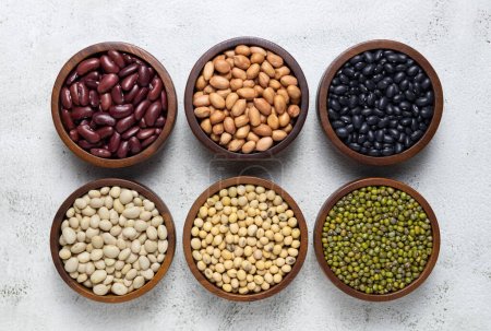 Photo for Top view of red kidney beans, peanuts, black kidney beans, white kidney beans, soybean and mung beans in wooden bowls on white background. cereals collection - Royalty Free Image