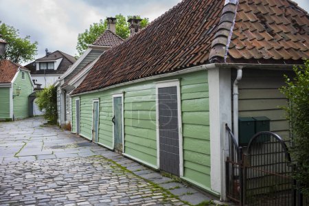 Téléchargez les photos : Une ruelle en pavé, située dans un quartier résidentiel de Bergen, en Norvège, photographiée lors d'une journée nuageuse et estivale. - en image libre de droit