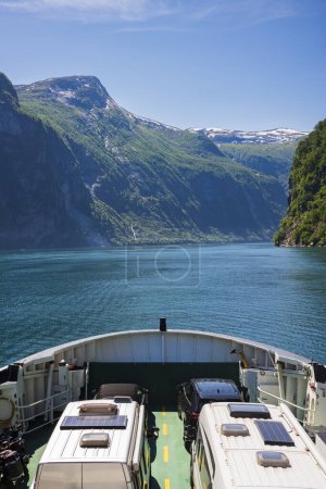 Photo for A ferry navigates the waters of Geirangerfjord between the villages of Geiranger and Hellesylt during a summer afternoon. - Royalty Free Image