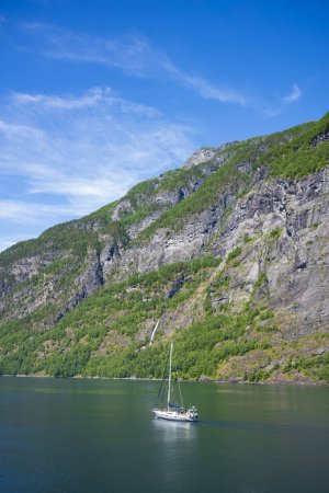 Photo for A lone sailboat navigates the waters of Geirangerfjord between the villages of Geiranger and Hellesylt during a summer afternoon. - Royalty Free Image