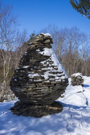Photo for The Bouchoux Trail near Long Eddy NY is a 5.5-mile hiking path that hugs the Delaware River, photographed under a few inches of snow during the winter. Stone stacks at the ledge of a valley view. - Royalty Free Image