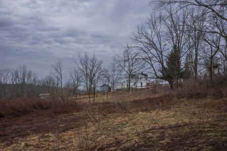 The Woodbourne Forest and Wildlife Preserve just south of Montrose, Pennsylvania, photographed during a cloudy winter day. An old farmhouse stands on a hill surrounded by bare trees. 