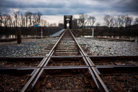 The intersection of two sets of railroad tracks intersecting near the Wabash River in Indiana during a cloudy, evening. 