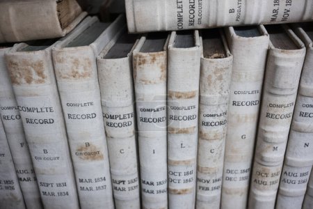 Stacks of books containing public records are neatly organized on a bookshelf found in the public library. 
