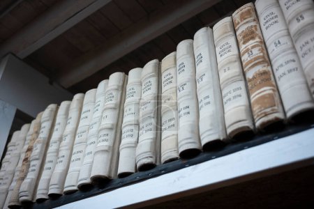 Montones de libros que contienen registros públicos se organizan cuidadosamente en una estantería que se encuentra en la biblioteca pública. 