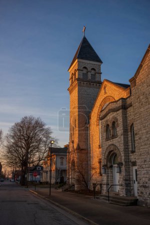 Der Schein des Sonnenuntergangs leuchtet auf dem Glockenturm einer katholischen Kirche aus Kopfsteinpflaster im Mittleren Westen der Vereinigten Staaten von Vincennes, Indiana. 
