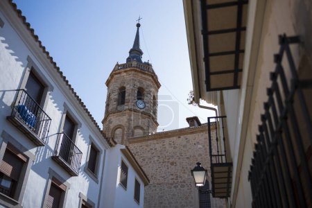 Tembleque, Spanien, ist ein kleines Dorf mit einer Kirche und einem Uhrturm im Zentrum, fotografiert an einem Sommertag ohne Wolken am Himmel. 