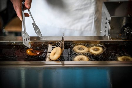 Téléchargez les photos : Une main de femme dans le processus de friture de petits beignets dans l'huile profonde - en image libre de droit