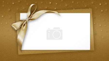 Foto de Billete de tarjeta de felicitación de regalo de Navidad en blanco con lazo de cinta dorada brillante, aislado en fondo beige con estrellas brillantes, plantilla de espacio de copia en blanco de vista superior para publicidad publicitaria de promoción banner - Imagen libre de derechos