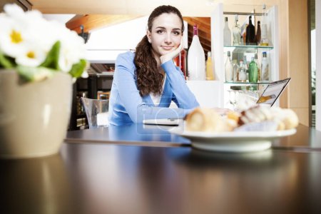 Foto de Hermosa joven sonriente sentada en la cafetería, heladería y pastelería. Retrato de chica morena con los pasteles en la mesa - Imagen libre de derechos