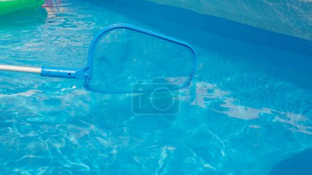 Photo for CLOSE UP: Unrecognizable pool cleaner uses a leaf net during seasonal maintenance works. Plastic pool skimmer cleans up tiny leaves from the glassy pool water. Person cleaning pool in the backyard - Royalty Free Image