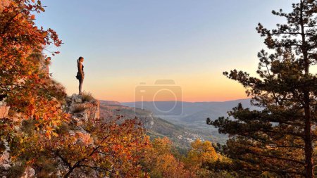 Photo for Young Caucasian woman rock climbing in Crni Kal, Slovenia observes the sunset from top of a cliff. Female traveler exploring rock climbing spots in Slovenia observes the golden sunrise. - Royalty Free Image