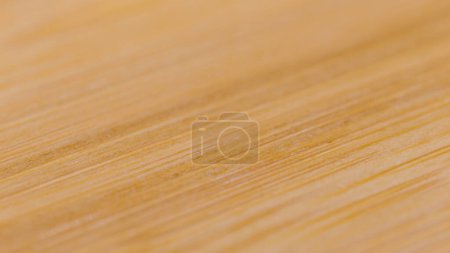 Foto de MACRO, DOF: Natural cutting board made of premium beech wood lies empty on the kitchen counter. Detailed close up shot of an empty handmade wooden cutting board. Macro view of a chef's chopping board. - Imagen libre de derechos