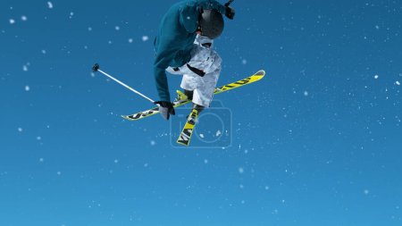 Foto de Spectacular shot of a young male freestyle skier jumping off a kicker and doing an extreme grab trick. Athletic male tourist skiing in the Slovenian Alps jumps into air and performs a spin trick - Imagen libre de derechos