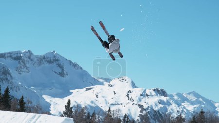 Photo for Athletic male tourist freestyle skiing in the Slovenian mountains does a flip trick on a sunny winter day. Spectacular shot of an extreme skier jumping off a kicker and doing a beautiful backflip. - Royalty Free Image