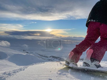 Photo for COPY SPACE, LENS FLARE: Unrecognizable woman shreds fresh snow while snowboarding off piste in the gorgeous Julian Alps on a sunny winter morning. Female snowboarder rides downhill at idyllic sunset. - Royalty Free Image
