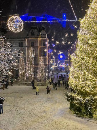 Foto de VERTICAL: Beautiful view of the golden lit Christmas tree in the middle of Preseren square on a cold night. Tourists explore the gorgeous Christmas themed Ljubljana. Festive square in European city. - Imagen libre de derechos