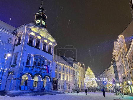 Foto de Scenic shot of the charming Ljubljana city center on a cold December evening with tourists and local people exploring the beautifully illuminated city streets. Festive square in touristy European city - Imagen libre de derechos