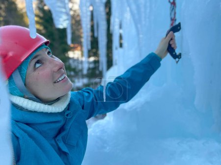 Photo for CLOSE UP, DOF: Smiling young Caucasian woman looks up the towering frozen waterfall before climbing it. Joyful female tourist prepares to climb an icy wall in the picturesque Slovenian mountains - Royalty Free Image