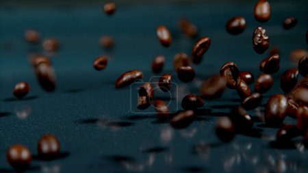 Photo for MACRO, DOF: Dark roasted arabica coffee beans fall onto the shiny black surface. Cinematic close up shot of mocha coffee beans falling and bouncing around the table. Scattered fragrant coffee. Beans. - Royalty Free Image