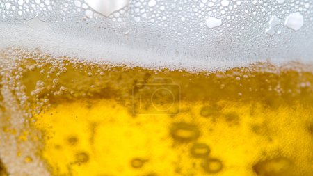 Foto de MACRO, DOF: Refreshing crisp golden pale ale gets poured into a large jug. Bubbling beer is splashing around the empty glass as it gets poured from a pub tap. White air bubbles rising to the top. - Imagen libre de derechos