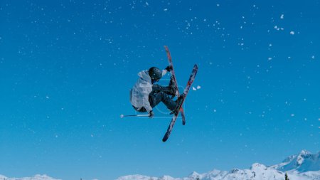 Téléchargez les photos : Expert freestyle skier rides up a kicker and does a breathtaking trick on a sunny day. Athletic male tourist rides off a massive snowpark kicker in Vogel, Slovenia and does a spectacular 360 grab. - en image libre de droit