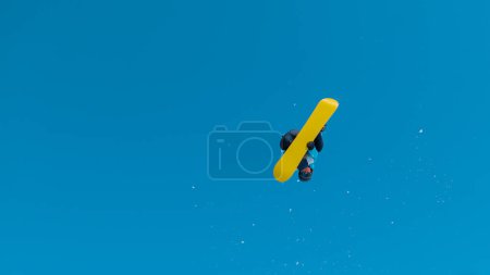 Photo for BOTTOM UP: Athletic snowboarder flying through the air and doing a 360 grab on a sunny winter day in the Slovenian mountains. Spectacular shot of a snowboarding pro doing awesome tricks and stunts. - Royalty Free Image
