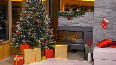 Photo for Beautifully decorated living room with fireplace and gifts under big Christmas tree on Christmas Eve. Luxury home with holidays decorations, burning fire and lots of presents under the Christmas tree - Royalty Free Image