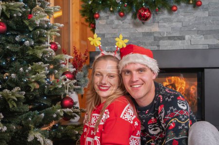 Photo for SLOW MOTION PORTRAIT: Cute young couple enjoying by the fire on Christmas day. Caucasian couple in love celebrating holidays by the living room fireplace in their decorated home on New Year's day - Royalty Free Image
