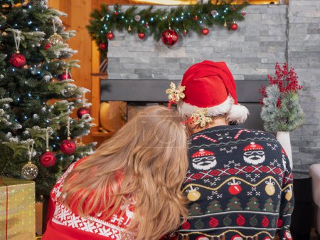 Photo for CLOSE UP: Unrecognizable young couple hugging by the fireplace under the Christmas tree on Christmas Eve. Affectionate man and wife embracing at home on New Year's eve. - Royalty Free Image