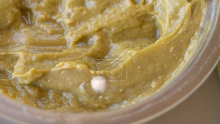 Photo for MACRO, DOF: White spores of mold spread across the surface of a jar of a hummus spread. Detailed close up shot of the inside of a glass half full of spoiled tahini paste. Disgusting rotting sauce. - Royalty Free Image