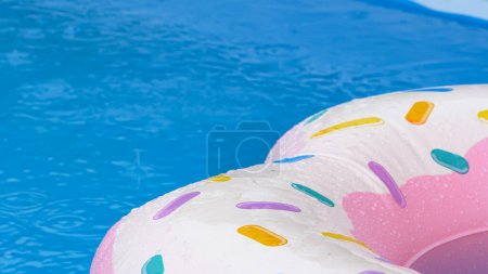 Téléchargez les photos : FERMER, DOF : À la fin de l'été, la pluie commence à tomber sur un beignet gonflable flottant autour d'une piscine vide. Des gouttes de pluie tombant dans la piscine créent des ondulations à la surface de l'eau turquoise. - en image libre de droit