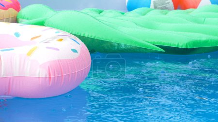 Foto de CERRAR, DOF: Gotas de lluvia caen sobre los juguetes de colores flotando alrededor de la piscina vacía en casa. Las últimas lluvias de verano caen sobre los objetos que quedan en la piscina. Gotas de lluvia crean ondulaciones en la superficie del agua. - Imagen libre de derechos