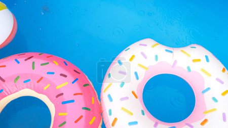Téléchargez les photos : TOP DOWN, CLOSE UP: Colorful inflatable donuts float around the empty home pool during a light rainstorm. Bad summer weather engulfs a private pool in someone's backyard full of inflatable toys. - en image libre de droit