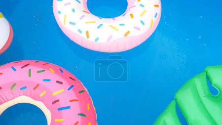 Téléchargez les photos : FERMER, HAUT DE PAGE : Les floaties colorées de la piscine sont laissées dans l'eau turquoise lors d'une tempête de pluie de fin d'été. Le mauvais temps engloutit une piscine privée dans le jardin de quelqu'un plein de jouets gonflables. - en image libre de droit