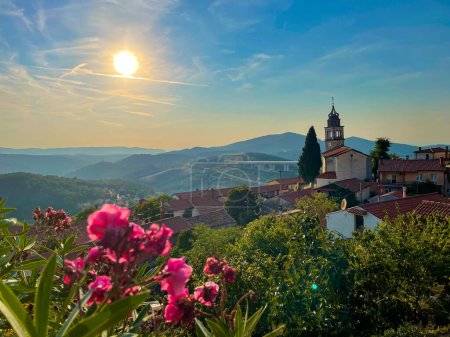 Téléchargez les photos : CLOSE UP, LENS FLARE: Scenic view of blossoming pink flowers and the spectacular vista of the Crni Kal landscape and viaduct. Golden summer sunbeams shine on the idyllic rural village of Crni Kal. - en image libre de droit