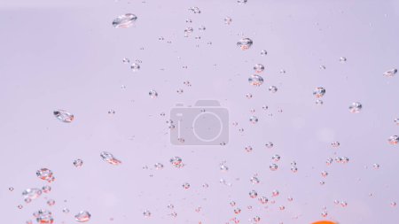 Téléchargez les photos : CLOSE UP, UNDERWATER, DOF: Tiny air bubbles rise up as a ripe red cherry tomato is dropped into the refreshingly cold tap water. Bubbles of air float up to the surface of the crystal clear water. - en image libre de droit