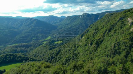 Téléchargez les photos : AÉRIAL : Vue aérienne panoramique de la vaste vallée de Slovénie, Europe couverte de forêts verdoyantes luxuriantes. Survoler les bois intacts dans les montagnes slovènes reculées. Montagnes verdoyantes pittoresques. - en image libre de droit