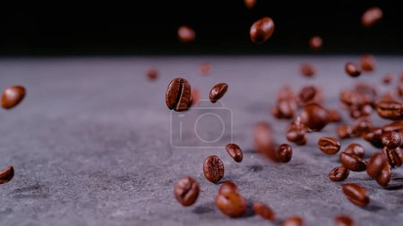 Photo for CLOSE UP, BOKEH: Scattered pile of aromatic coffee grains in air on gray background. Roasted coffee seeds falling on surface caught in motion. Detailed view of flying coffee beans with shallow focus. - Royalty Free Image