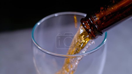 Foto de CLOSE UP, BOKEH: Detailed view of pouring fresh cold beer from bottle into the beer glass. Gentle blurred movement while pouring beverage from bottle to glass. Refreshment for summer days. - Imagen libre de derechos