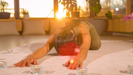 Photo for Pretty Asian woman at restful yoga pose in relaxing home atmosphere. Young Asian female person doing yoga practice at home. Healthy indoor leisure activity for relaxation and flexibility. - Royalty Free Image